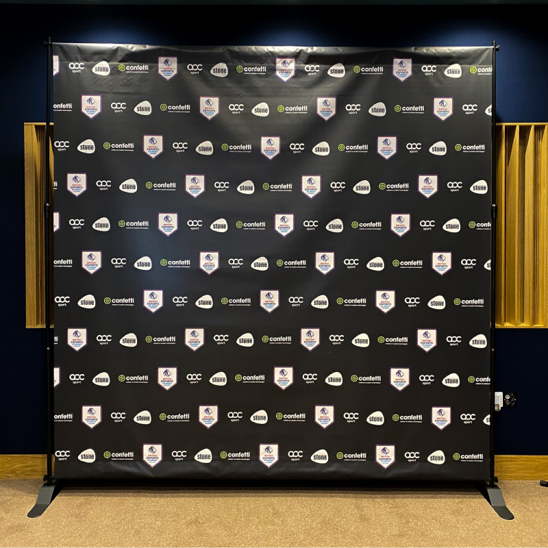 A large square custom printed backdrop for photos. The Confetti and British Esports logos are repeated horizontally on a black background.