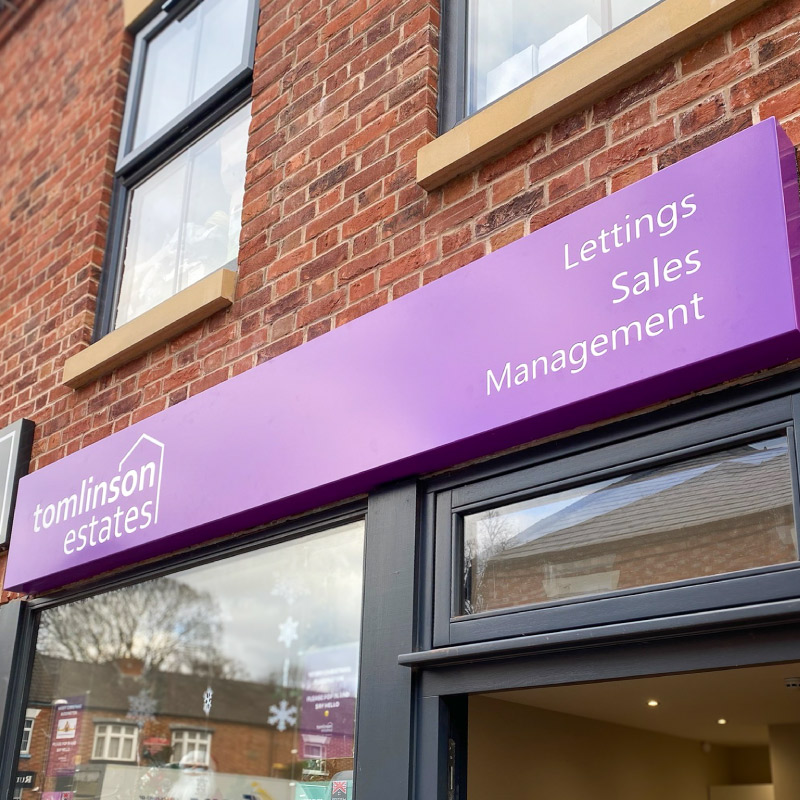 Tomlinson Estates Illuminated tray sign. The tray sign is purple with their logo cut out of it and LED illumination behind it.