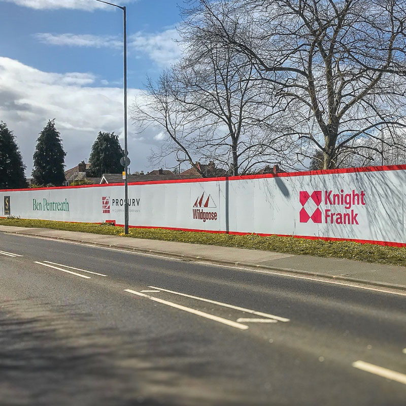 Hoarding around the edge of a consutruction site with printed logos.